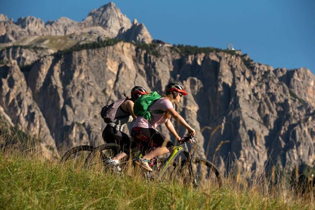 E-bike a Cortina d'Ampezzo Mietres, due persone che pedalano sulla bici, sullo sfondo monte Faloria